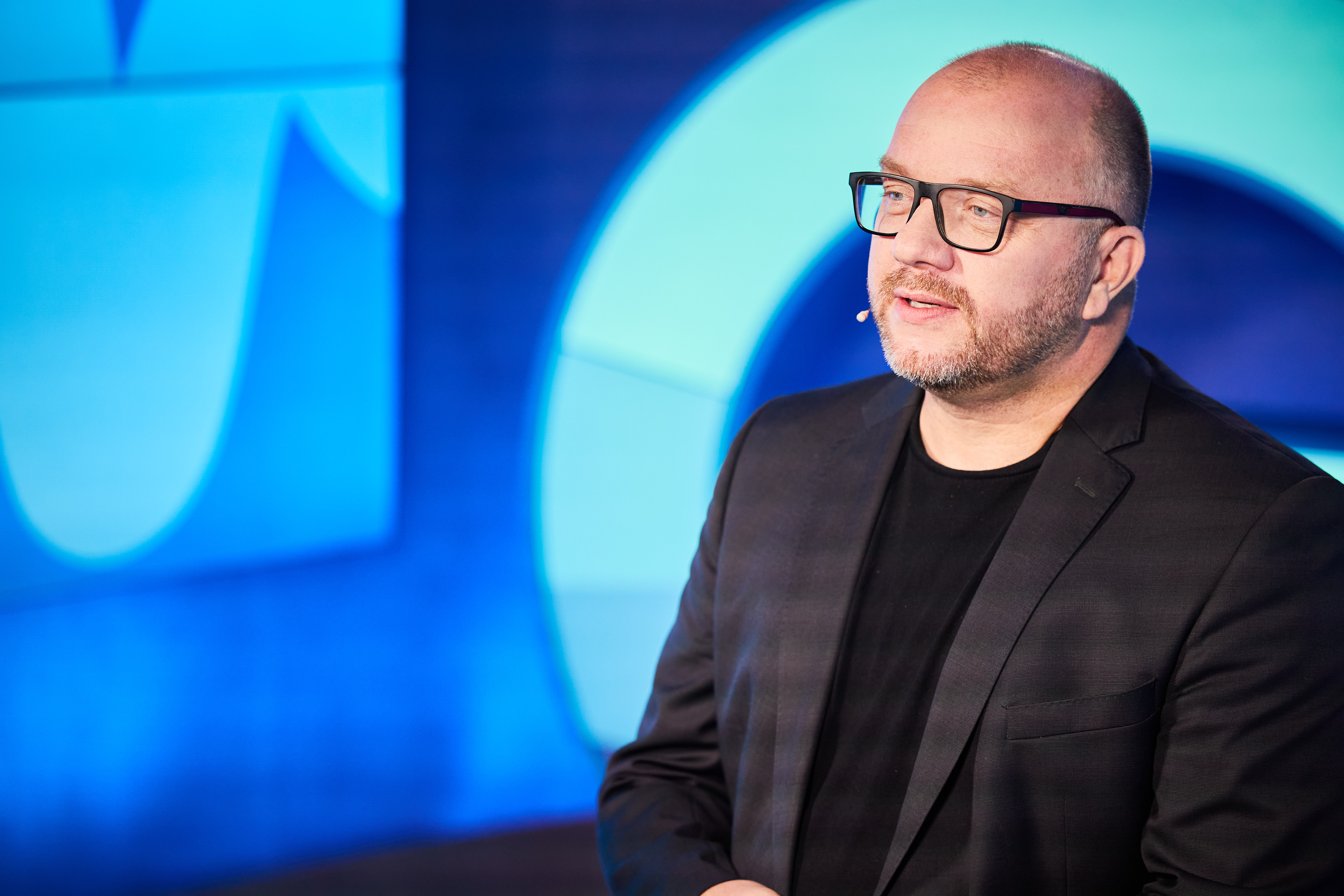 Michael Ehlers bei einer Keynote vor blauem Bühnenhintergrund